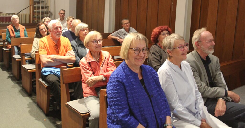 Publikum in den Kirchenbänken lauscht den Texten